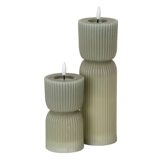 Two grey carved LED candles of different heights standing together.