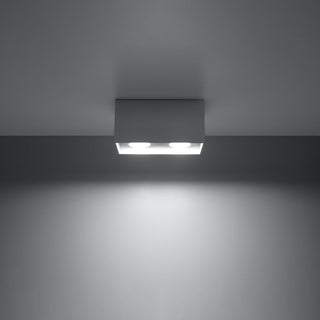 Illuminated grey rectangular light fixture demonstrating the downward beam spread on a wall.