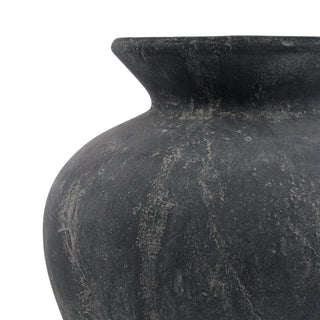 Close-up detail showing the curved shoulder of the dark grey ceramic vase and the heavily weathered surface texture.