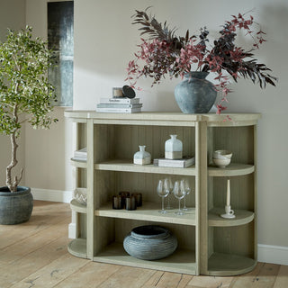 The Amalfi vase sits on a pale wooden shelving unit, styled with dark red decorative branches and books.