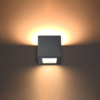 Grey ceramic wall light switched on, showing the warm ambient light cast upwards and downwards.