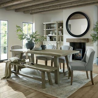 Styled dining room scene showing multiple grey upholstered chairs around a large wooden table.