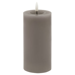 Plain front-on shot of a tall grey LED pillar candle with a melted wax effect top and faux flame on white.
