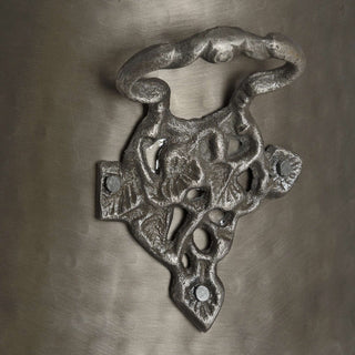 Close-up of the ornate, textured cast metal side handle mount attached to the grey bucket surface.