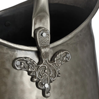 Close-up of the carrying handle connection point and the ornate cast metal mount attached to the bucket rim.