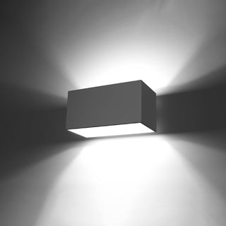 Illuminated grey aluminium wall lamp demonstrating the upward and downward light spread against a dark background.