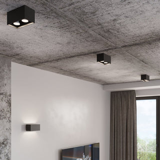 Multiple grey lamps surface-mounted on a raw concrete ceiling, demonstrating use as overhead lighting.