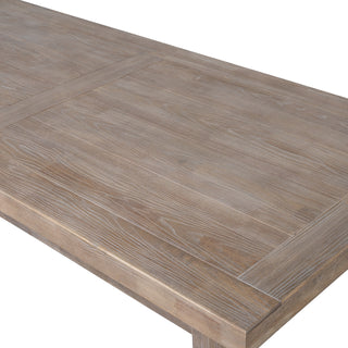 Detail of the light wood dining table surface, showing the prominent grain texture and rectangular panelled design.