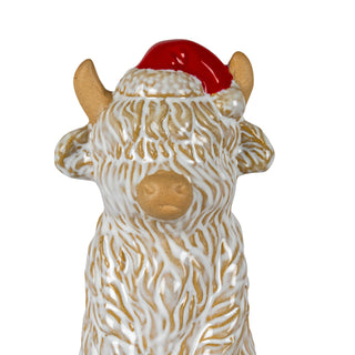 Front view close-up of the ceramic Highland cow's face, red hat, and shaggy textured coat.