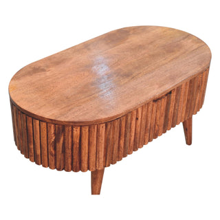 High angle view of the oval coffee table, showing the smooth wooden tabletop and the vertical ribbed sides.