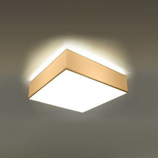 Illuminated square ceiling light fixture mounted flush, showing the warm upward glow onto the ceiling.