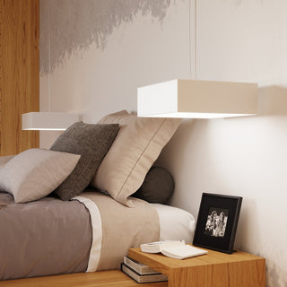 Close-up of square pendant light above neutral bedding and wooden bedside furniture.