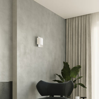 White layered wall lamp unlit in a room corner, beside a window with sheer and heavy grey curtains.