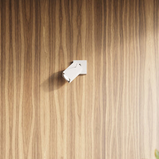 White adjustable spotlight mounted on a vertical wood panel wall with a strong vertical grain.