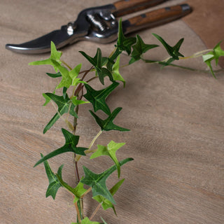 Detail shot of the star-shaped plastic ivy leaves and stem, with shears resting on a wooden surface.