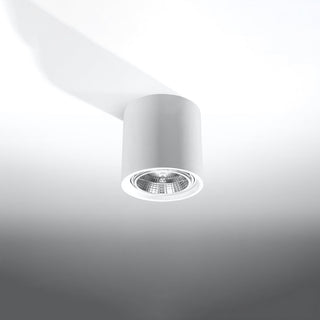 Angled view of the white ceramic cylinder light casting a long shadow, showing the recessed bulb.