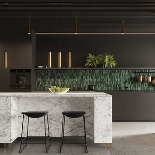Gold cylindrical pendant lights suspended over a marble island in a dark, contemporary kitchen interior.