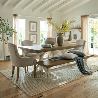 Bracken fern spray in a vase on a wooden dining table, styled in a bright, rustic dining room setting.