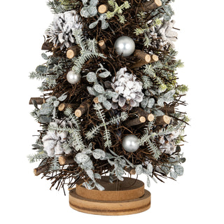 Close-up detail of the twig texture, frosted pinecones, and silver baubles, showing the wooden base.