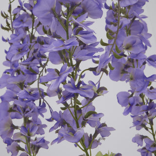 Close-up detail of the artificial purple wisteria flowers showing individual petals and green stems.