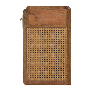 Side view of the mango wood bedside cabinet showing the large woven cane webbing panel and protruding brass handle.