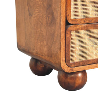 Corner detail showing the rounded base of the chestnut nightstand resting on two large, dark wooden ball feet.