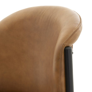 Close-up detail of the tan leather backrest curve and stitching where it meets the black metal frame.