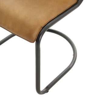 Detail of the leather seat texture and the curve of the black metal cantilever base.