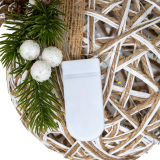 Detail of the white LED battery pack, artificial pine sprigs, and three white glitter-covered berries.