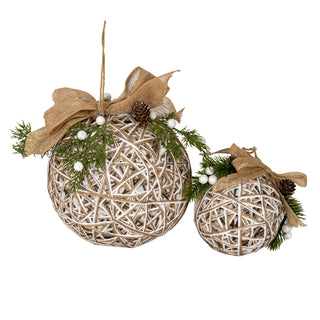 Two sizes of the woven rattan bauble side-by-side, decorated with jute ribbon, pine sprigs, pinecones, and white berries.
