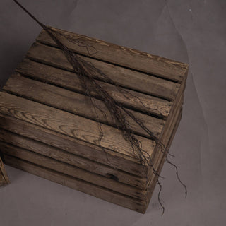 Artificial dark branch spray lying across stacked rustic wooden crates.