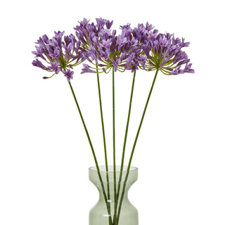 Multiple artificial lilac agapanthus stems arranged in a pale green glass vase.
