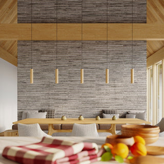 Five wooden cylindrical pendants hung linearly over a dining table against a textured grey stone wall.