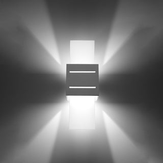 Illuminated wall light casting four distinct beams of light onto the surrounding wall surface.