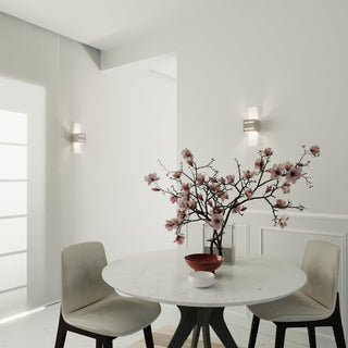Pair of grey wall lamps illuminating a white wall in a modern dining space with a marble table.