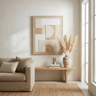 Lumera canvas artwork hanging above a wooden bench, with a linen sofa and pampas grass in a bright, neutral room.