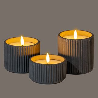 Three dark ribbed LED candles in different sizes, showing the bright internal glow and white flames.