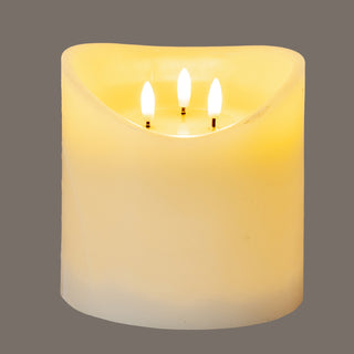 Close-up of the cream LED candle illuminated, highlighting the warm glow and three internal wicks.