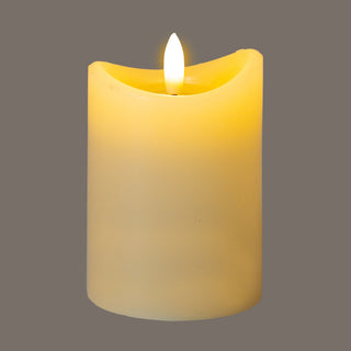 Illuminated cream LED candle showing a warm glow through the wax body, set against a plain grey background.
