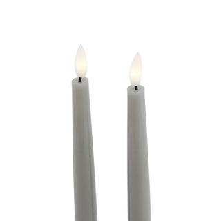 Close-up detail of the illuminated white flicker flames on two grey LED taper candles.
