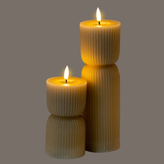 Close-up of two natural stone effect LED candles showing the fluted texture and carved hourglass shape.