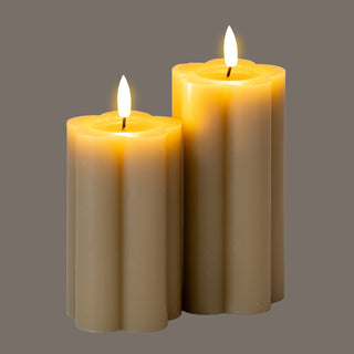 Two stone-coloured LED candles glowing warmly against a plain grey background.