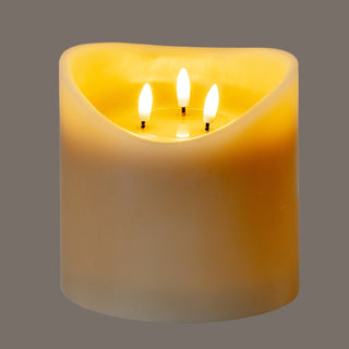Front view of the taupe LED candle, showing the warm light radiating through the wax and the three illuminated wicks.