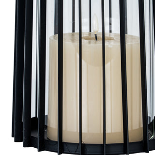 Black metal lantern base detail with lit cream faux pillar candle visible through the vertical bars.