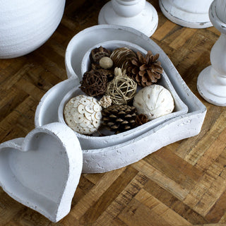 Two heart dishes nested and filled with potpourri, third dish displayed separately on a wooden surface.