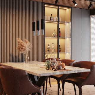Cluster of three matte black and chrome pendant lights hanging above a marble dining table in a styled interior.