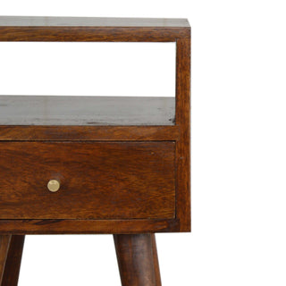 Tight close-up of the chestnut bedside table showing the open cubby, drawer front, and small brass handle detail.