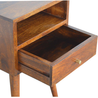 Close-up showing the chestnut bedside table's storage cubby and the drawer pulled open with a brass knob.