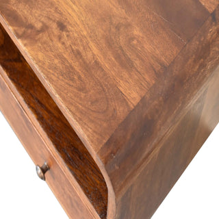 Detail shot showing the chestnut wood grain, the curved front edge, and the open shelf above the drawer.
