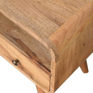Close detail of the curved top corner joint, showing the natural wood grain, open shelf, and brass drawer knob.
